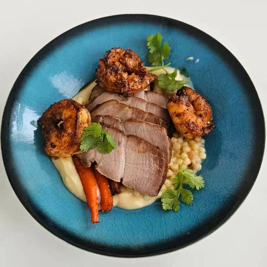 Sliced pork with blackened shrimp and roasted carrots